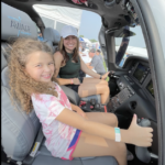 Mom and daughter sitting in plane smiling